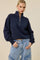 woman wearing a navy blue half-zip pullover sweater with balloon sleeves and high-waisted denim wide-leg jeans