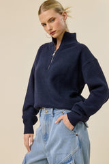 woman wearing a navy blue zip-up sweater with a high collar and relaxed fit, paired with light blue baggy jeans