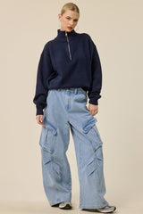 woman wearing a navy blue zip-up fleece sweater and light blue baggy cargo jeans