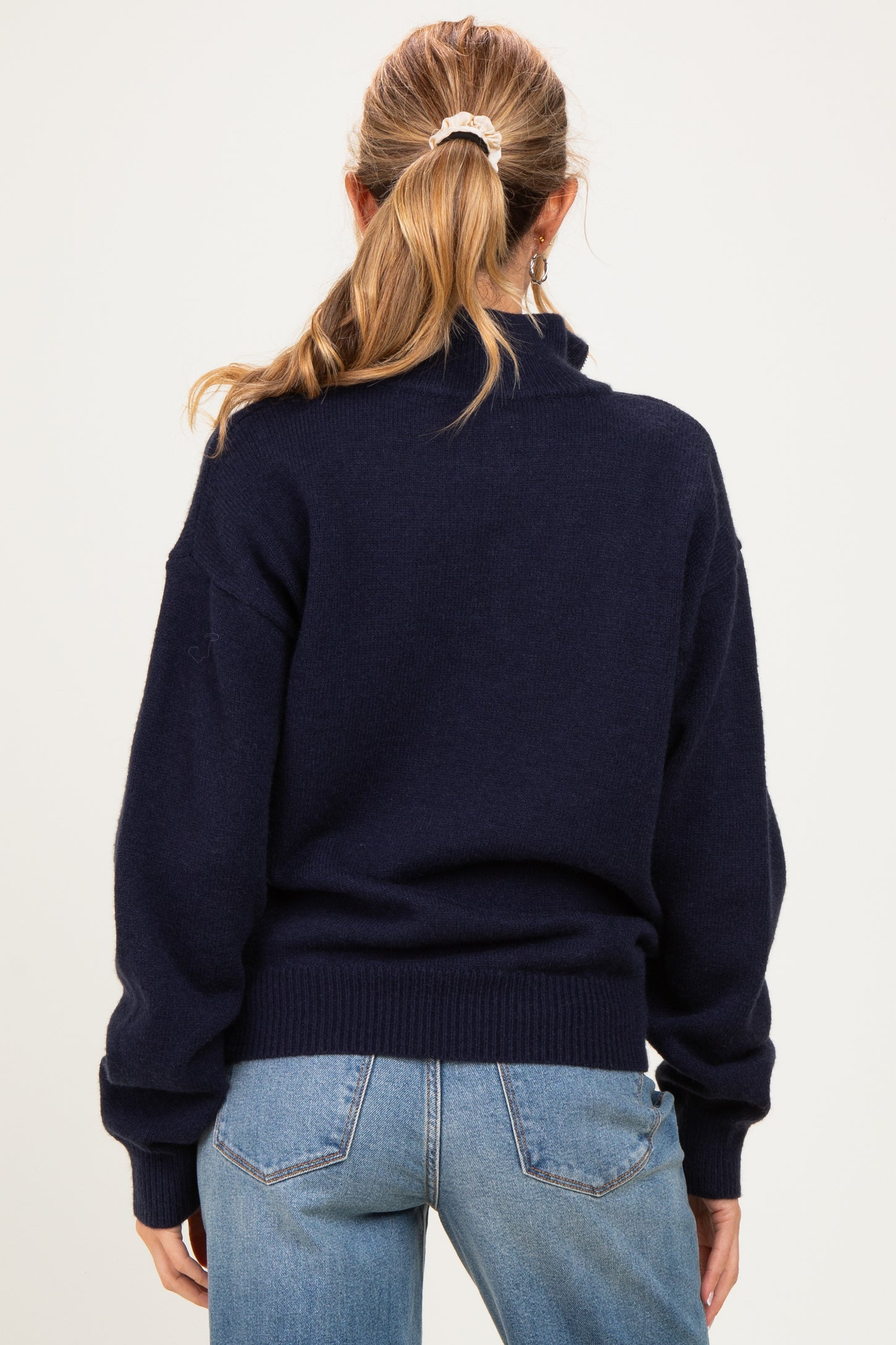 woman wearing a navy blue maternity sweater with cuffed sleeves and a relaxed fit, seen from the back