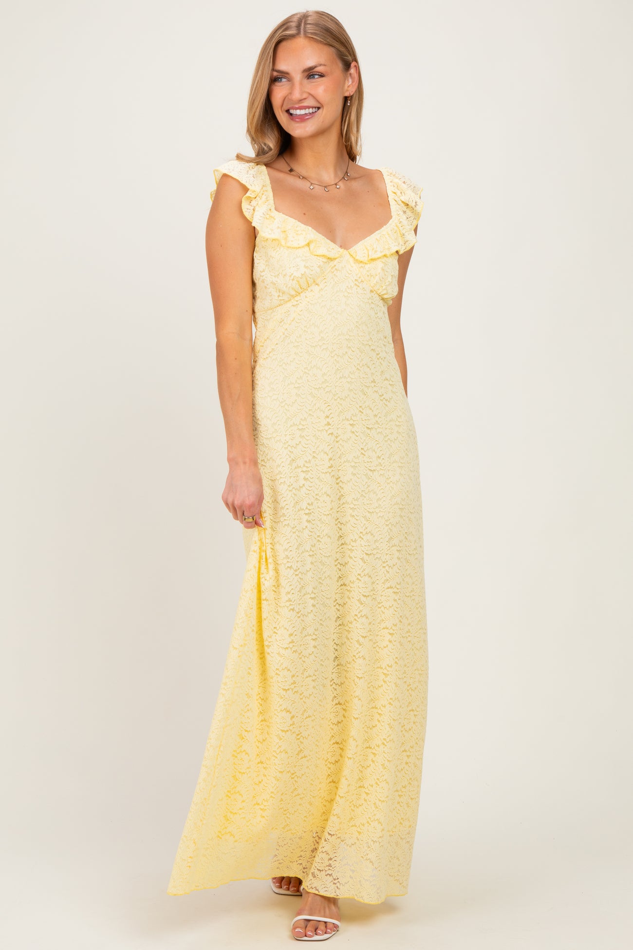 woman wearing a yellow lace maxi dress with ruffle sleeves and a sweetheart neckline