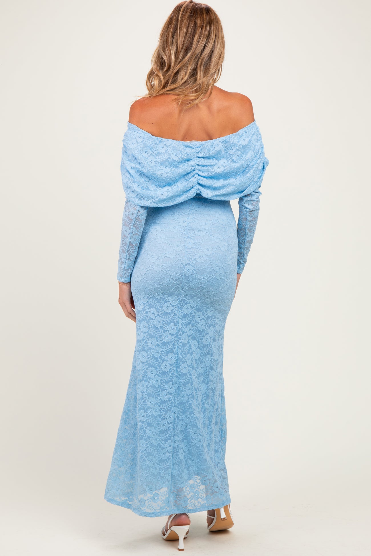 woman wearing a light blue off-the-shoulder lace maternity gown with a fitted silhouette and long sleeves