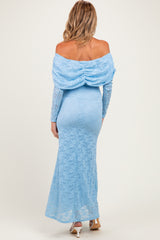 woman wearing a light blue off-the-shoulder lace maternity gown with a fitted silhouette and long sleeves