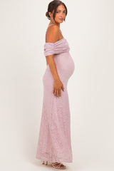 woman wearing a light pink off-shoulder lace maternity gown with a visible baby bump