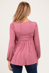 woman wearing a dusty rose long sleeve maternity top with a pleated waist and relaxed fit, showing her back