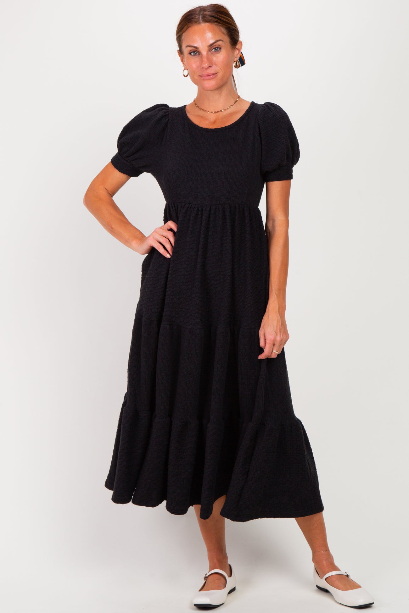 woman wearing a black puff sleeve midi dress with tiered ruffles and a round neckline