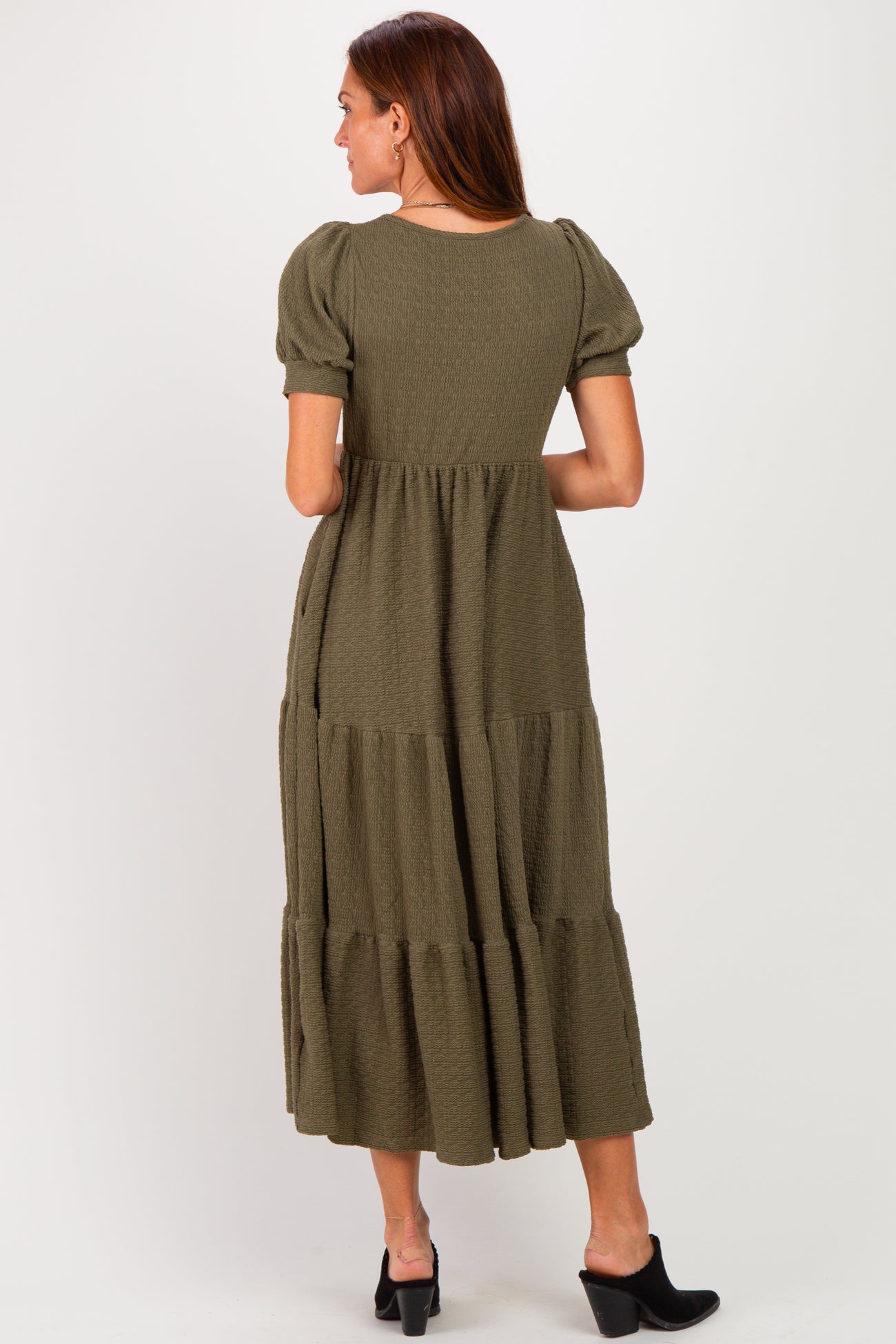 woman wearing an olive green maxi dress with puff sleeves and a tiered skirt, shown from the back