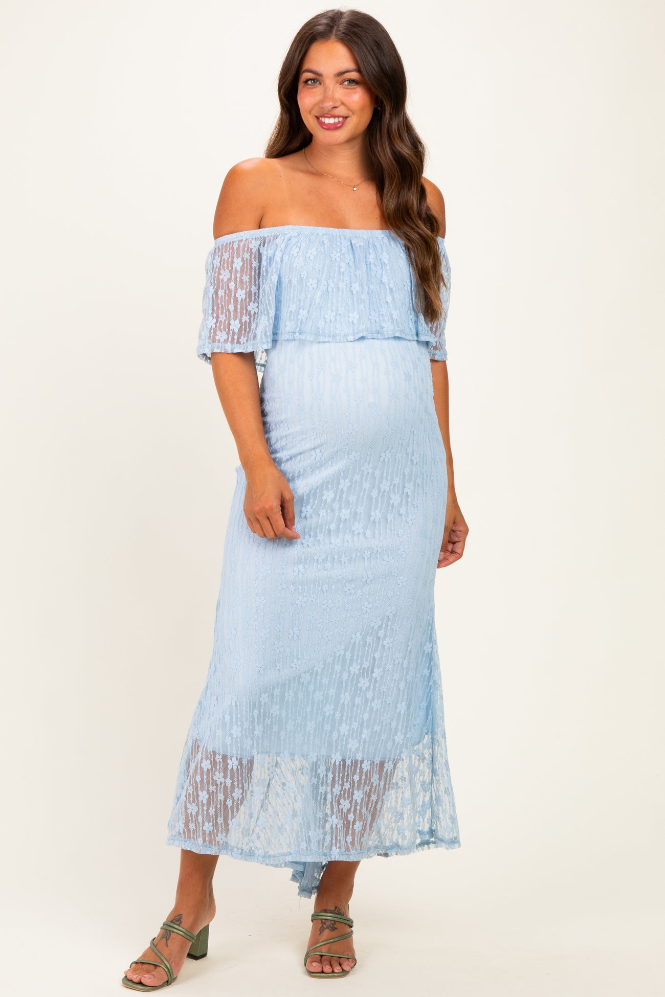 woman wearing a light blue off-the-shoulder maternity dress with sheer lace details and a visible baby bump