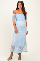 woman wearing a light blue off-the-shoulder maternity dress with sheer lace details and a visible baby bump