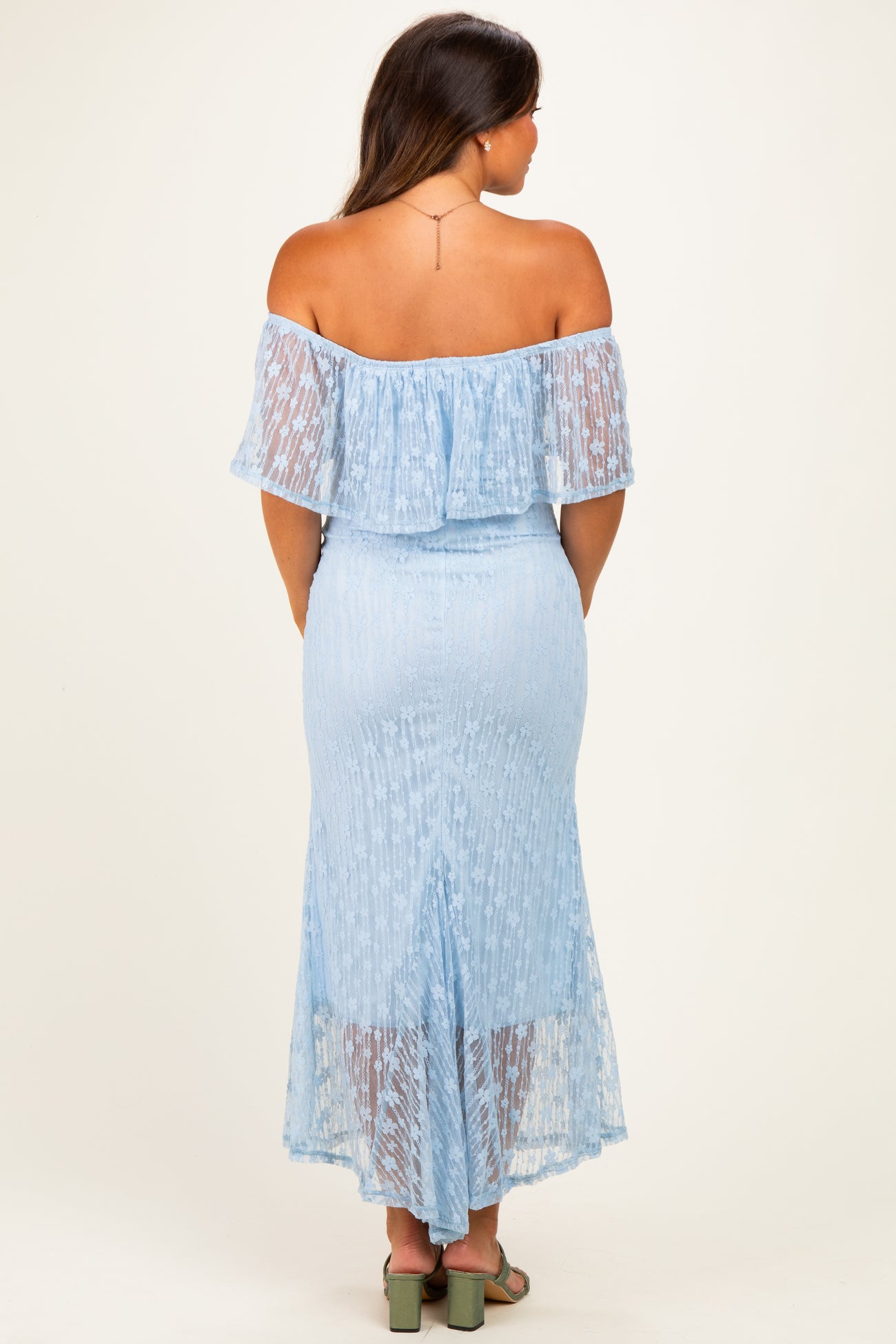 woman wearing a light blue off-the-shoulder maternity dress with a ruffled hem and a fitted silhouette, showcasing a baby bump from the back