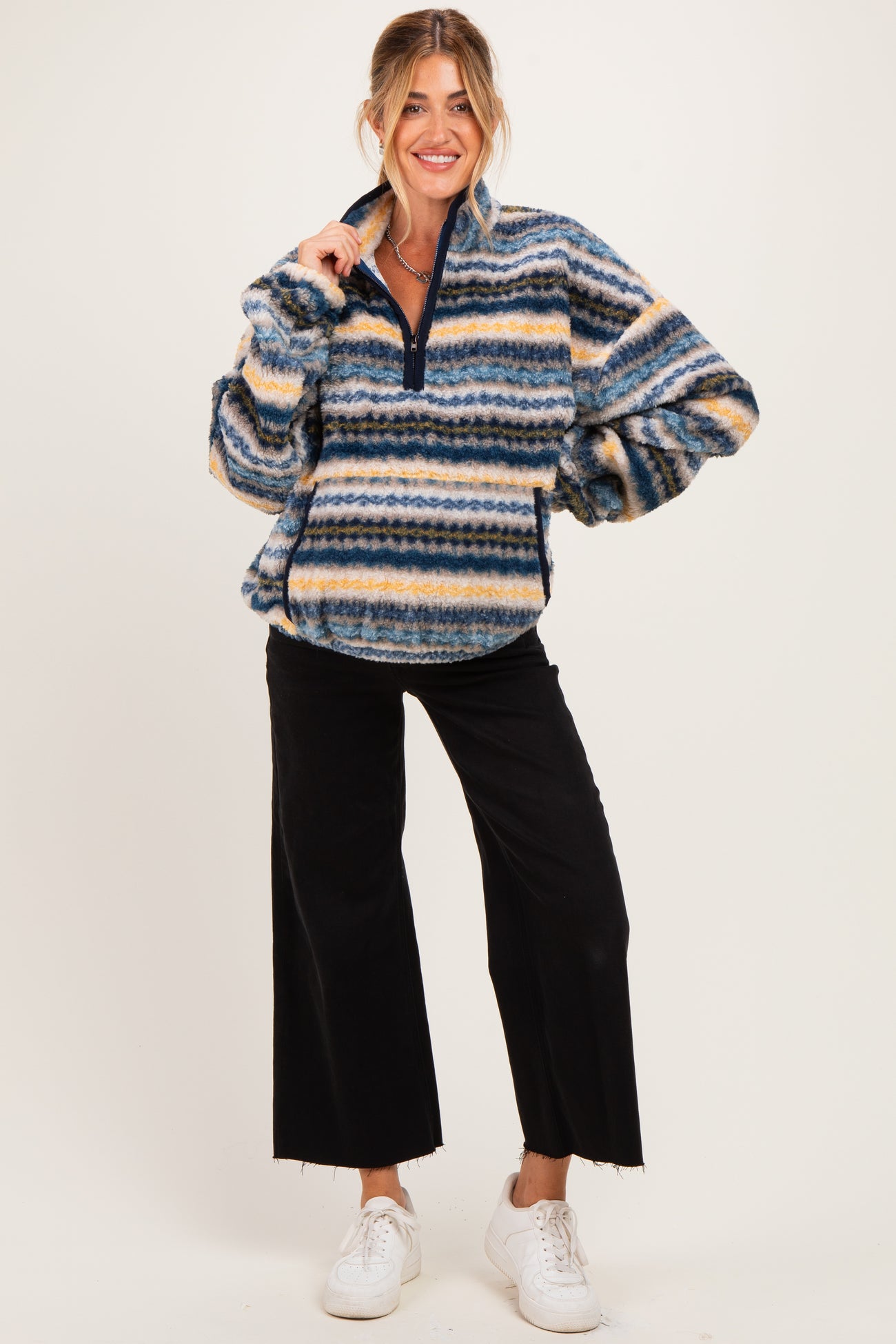 woman wearing a multicolored striped maternity pullover with half zip and oversized sleeves, paired with black wide-leg pants