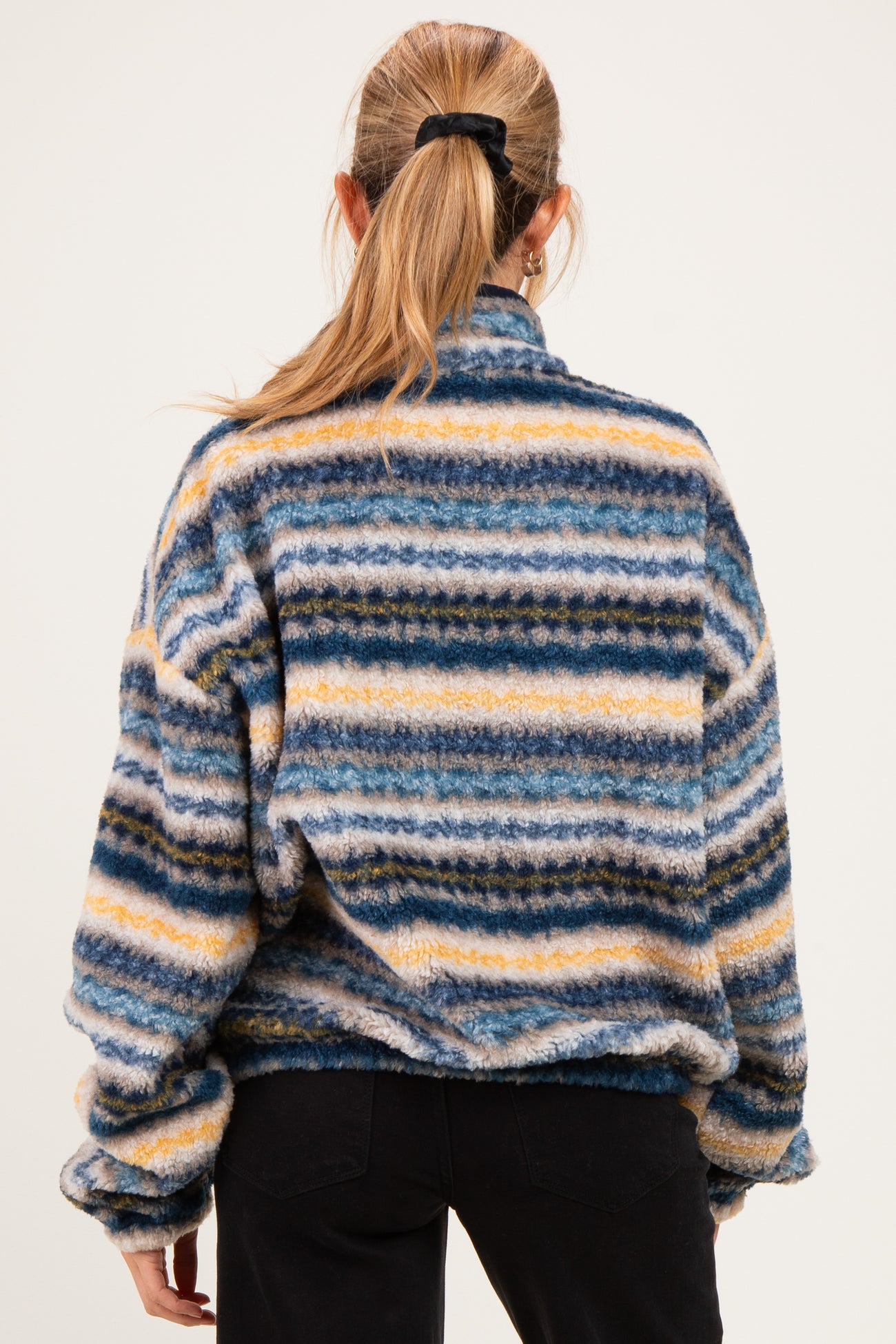 woman wearing a multicolored striped maternity fleece pullover with a high collar, visible from the back