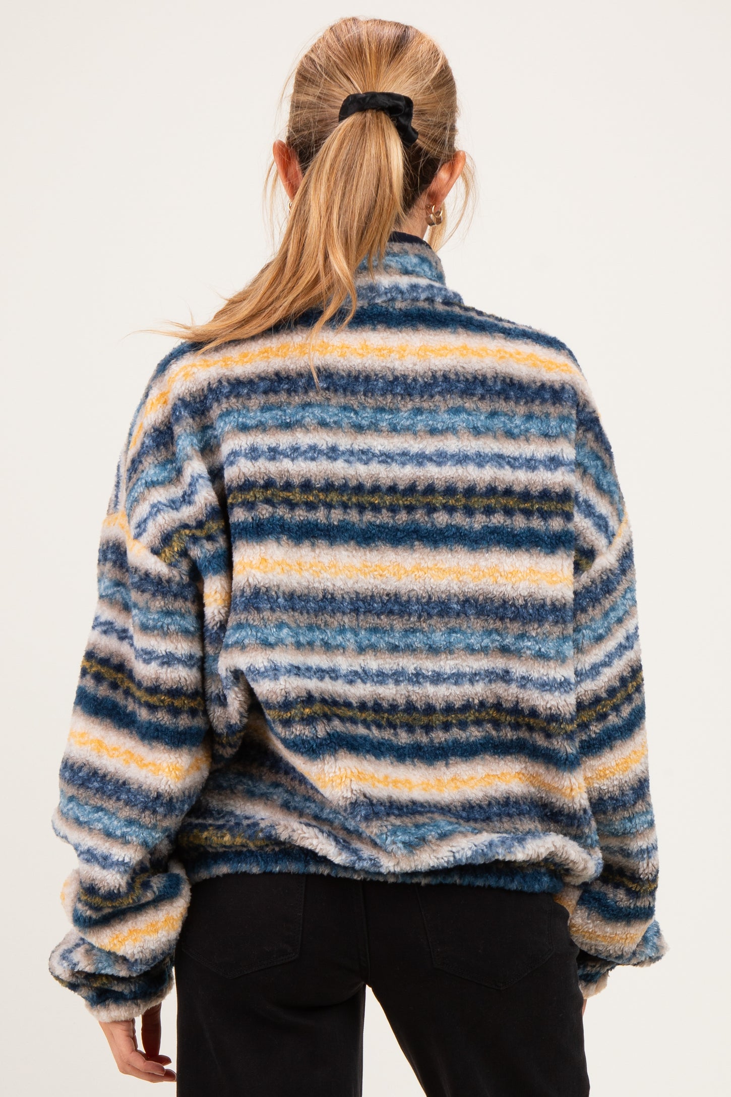 woman wearing a multicolored striped maternity fleece pullover with a high collar, visible from the back