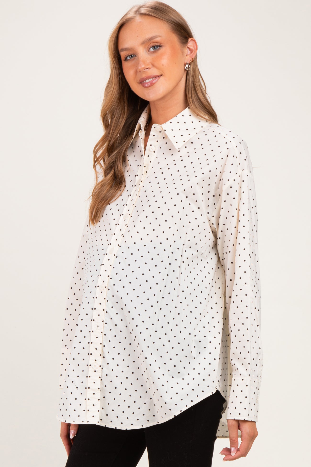 woman wearing a white maternity shirt with black polka dots and a visible baby bump