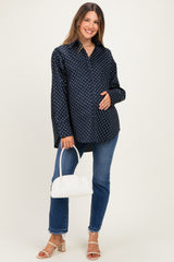 woman wearing a navy polka dot maternity button-up shirt and blue jeans, cradling her baby bump and holding a white handbag