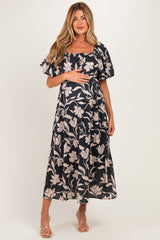 woman wearing a navy floral maternity maxi dress and holding her baby bump
