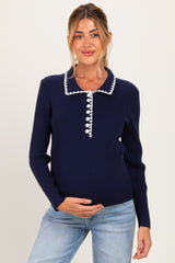 woman wearing a navy maternity sweater with decorative white buttons and collar, showcasing her baby bump