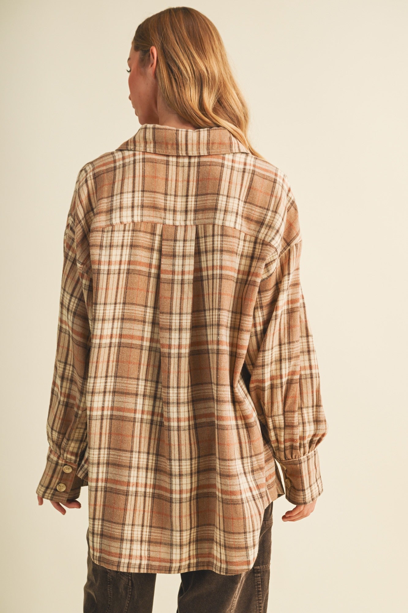 woman wearing a brown and beige checkered oversized flannel shirt with long sleeves and button details