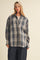 woman wearing a navy and cream plaid button-up shirt with a relaxed fit and a beige baseball cap