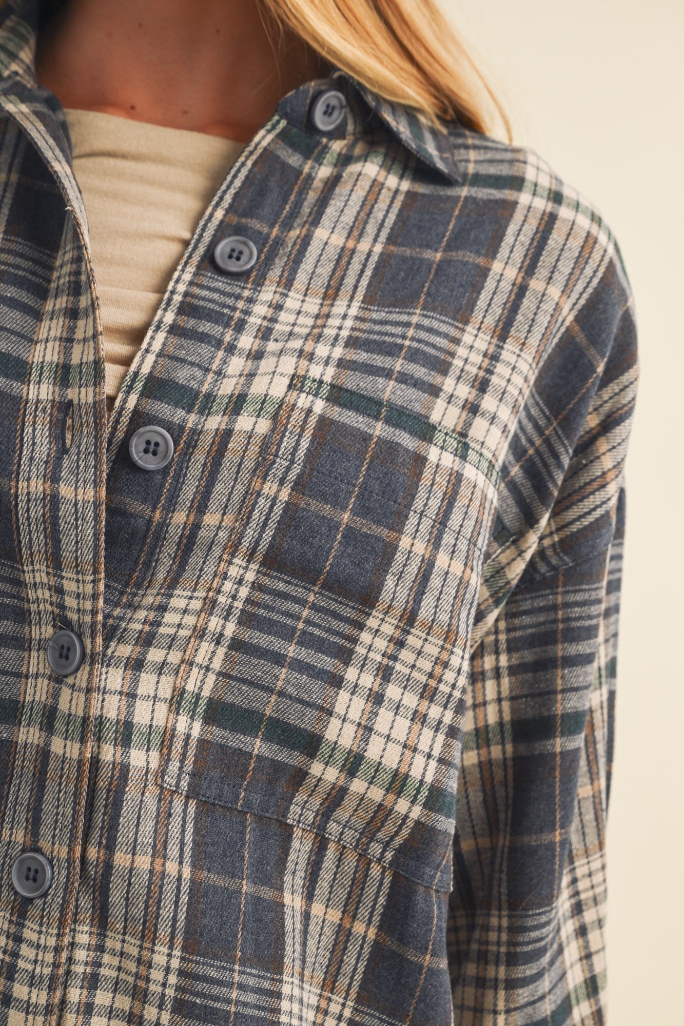 woman wearing a blue and beige plaid flannel shirt with a chest pocket and button-up detail