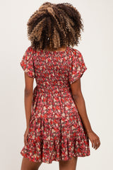 woman wearing a red floral smocked maternity dress with a flared skirt