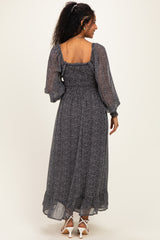 woman wearing a black and white floral print maternity maxi dress with balloon sleeves and smocked detailing