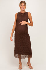 woman wearing a brown lace maternity dress and gently holding her baby bump