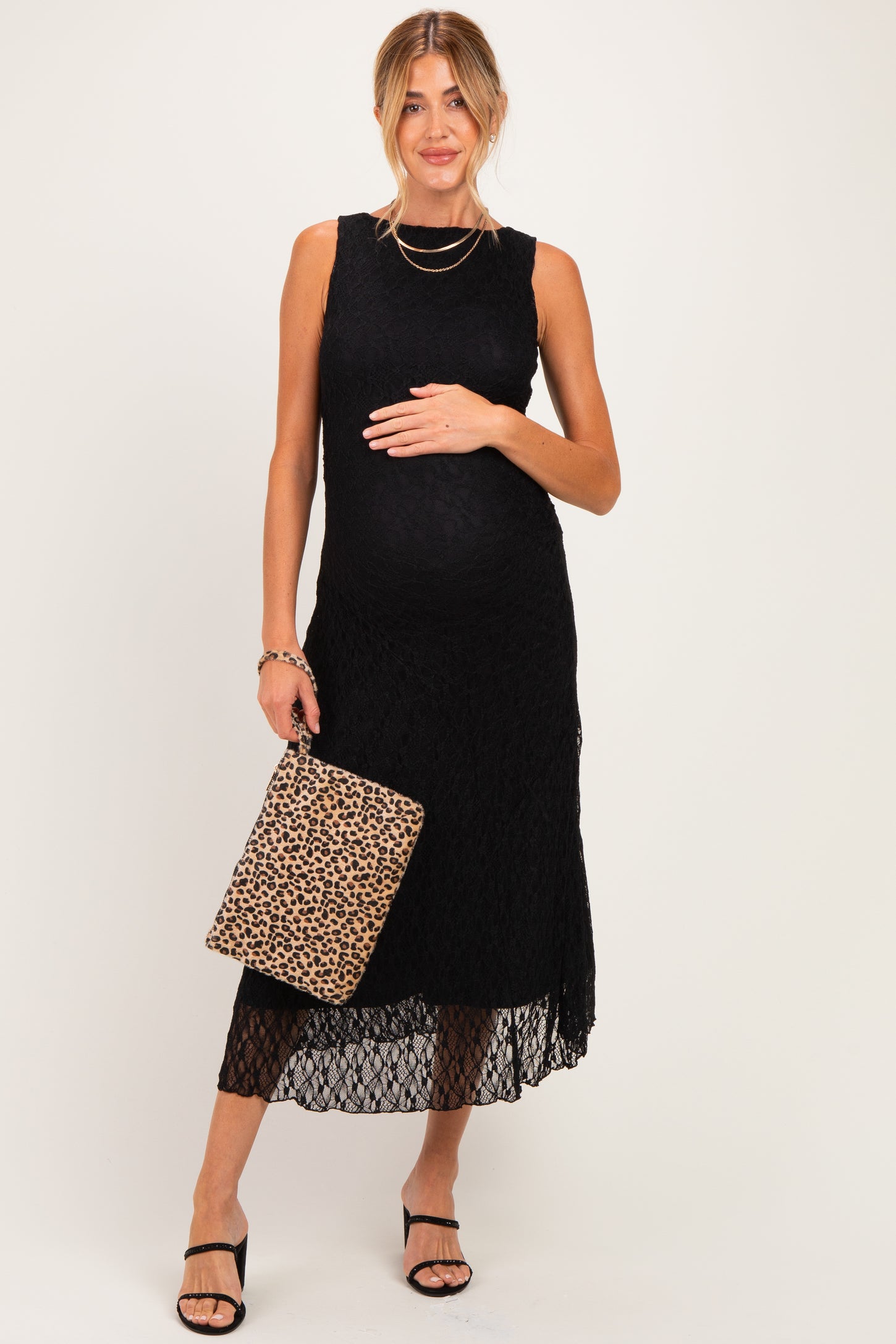 woman wearing a black lace maternity dress with a baby bump and holding a leopard print handbag
