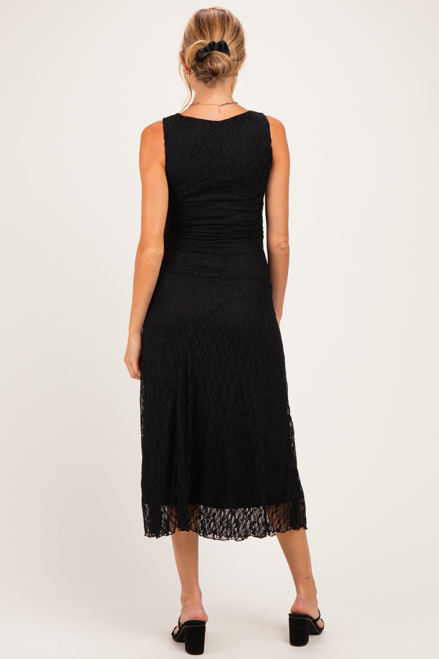 woman wearing a black lace midi maternity dress, showing the back view with a fitted bodice and flared skirt
