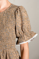 woman wearing a brown floral smocked blouse with puffed sleeves and lace trim detailing