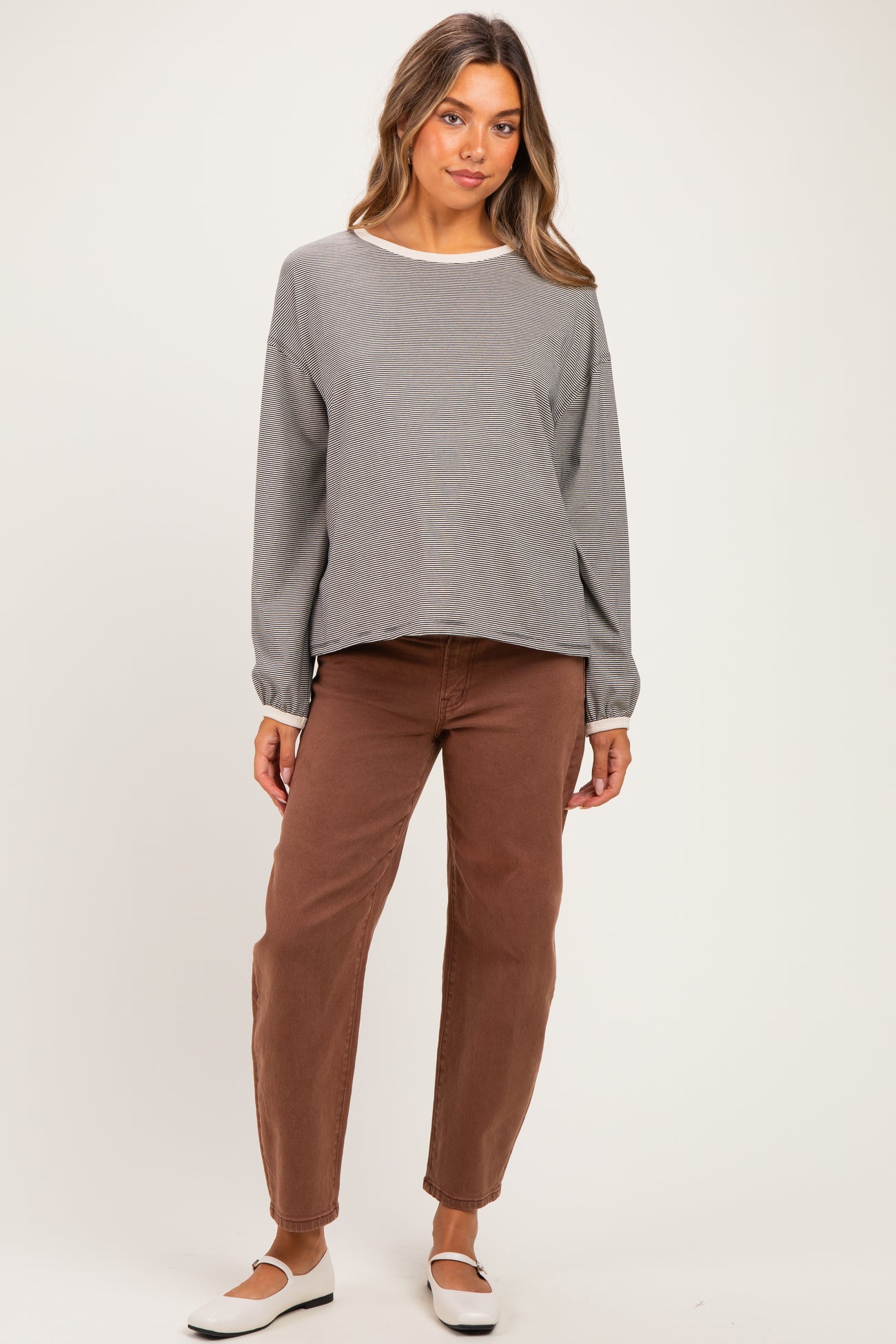 woman wearing a gray striped long sleeve maternity top and brown maternity pants with a relaxed fit