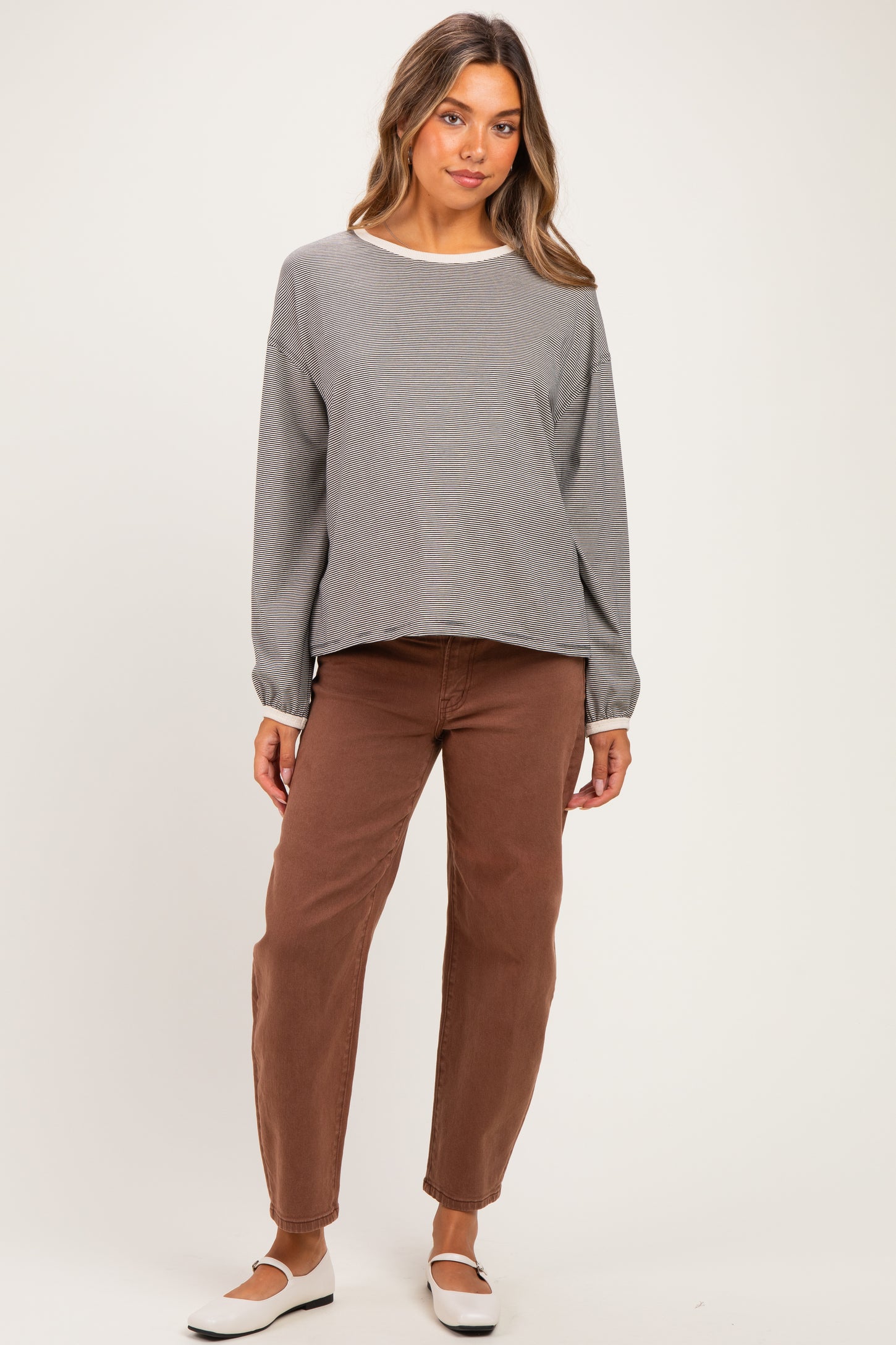 woman wearing a gray striped long sleeve maternity top and brown maternity pants with a relaxed fit
