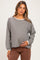 woman wearing a gray striped maternity top with long sleeves and a relaxed fit, holding her baby bump