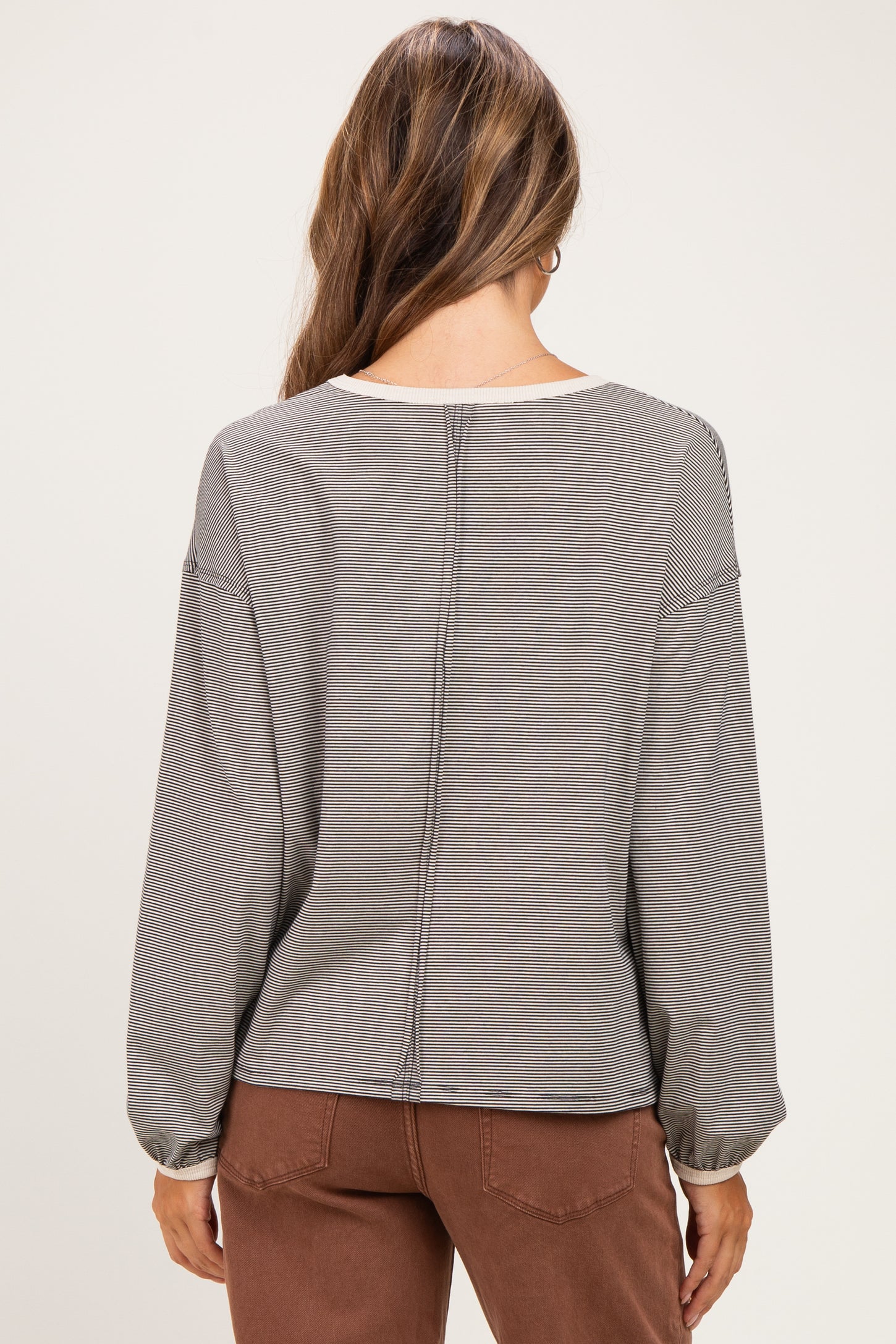 woman wearing a gray striped long sleeve maternity top, showing the back view with gathered sleeves