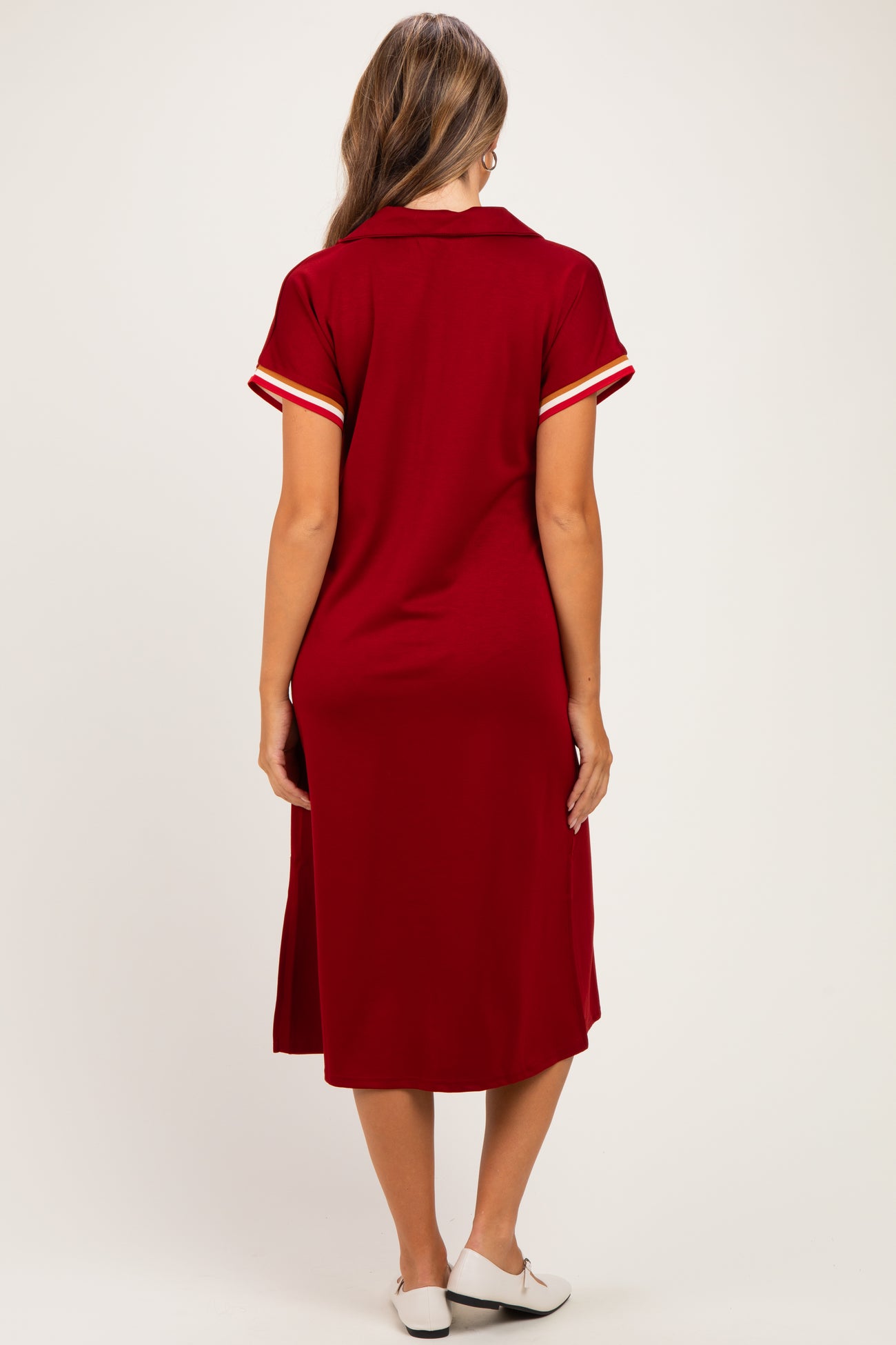 woman wearing a burgundy maternity dress with a collared neckline and striped sleeves, view from the back
