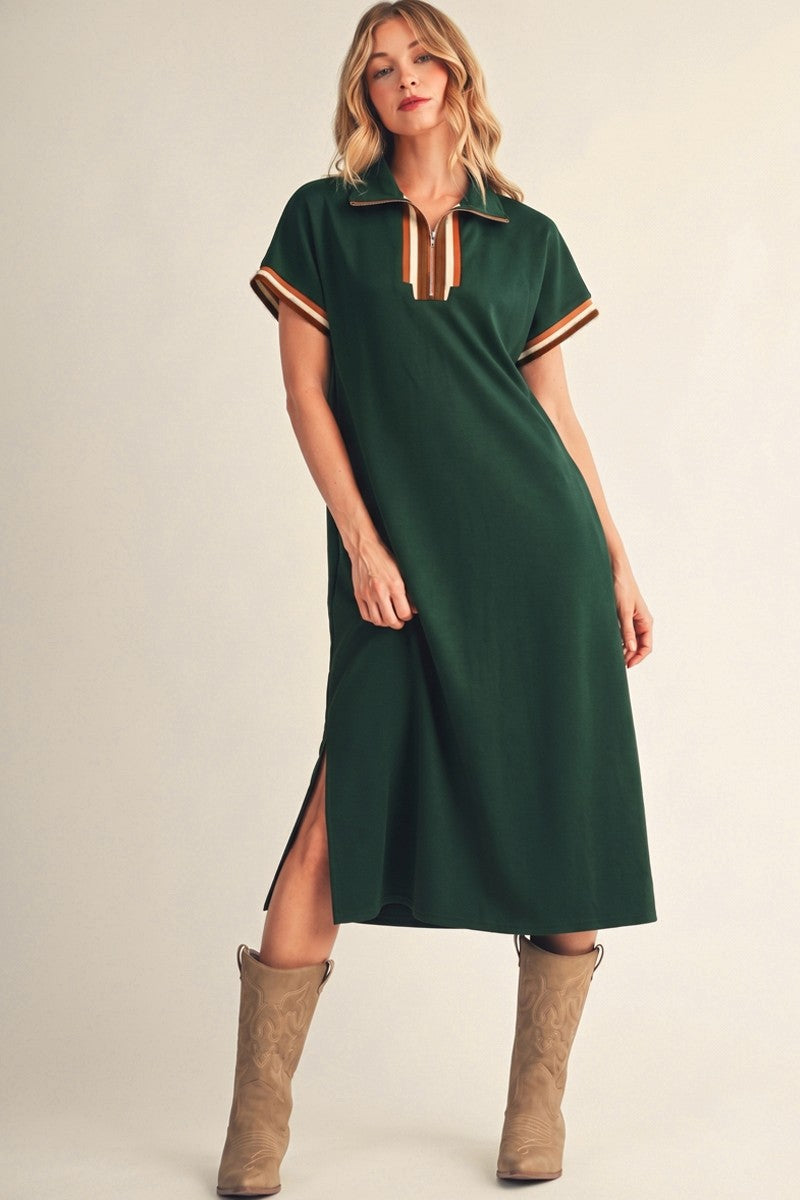 woman wearing a green midi dress with short sleeves, a collar, and side slits, paired with tan cowboy boots