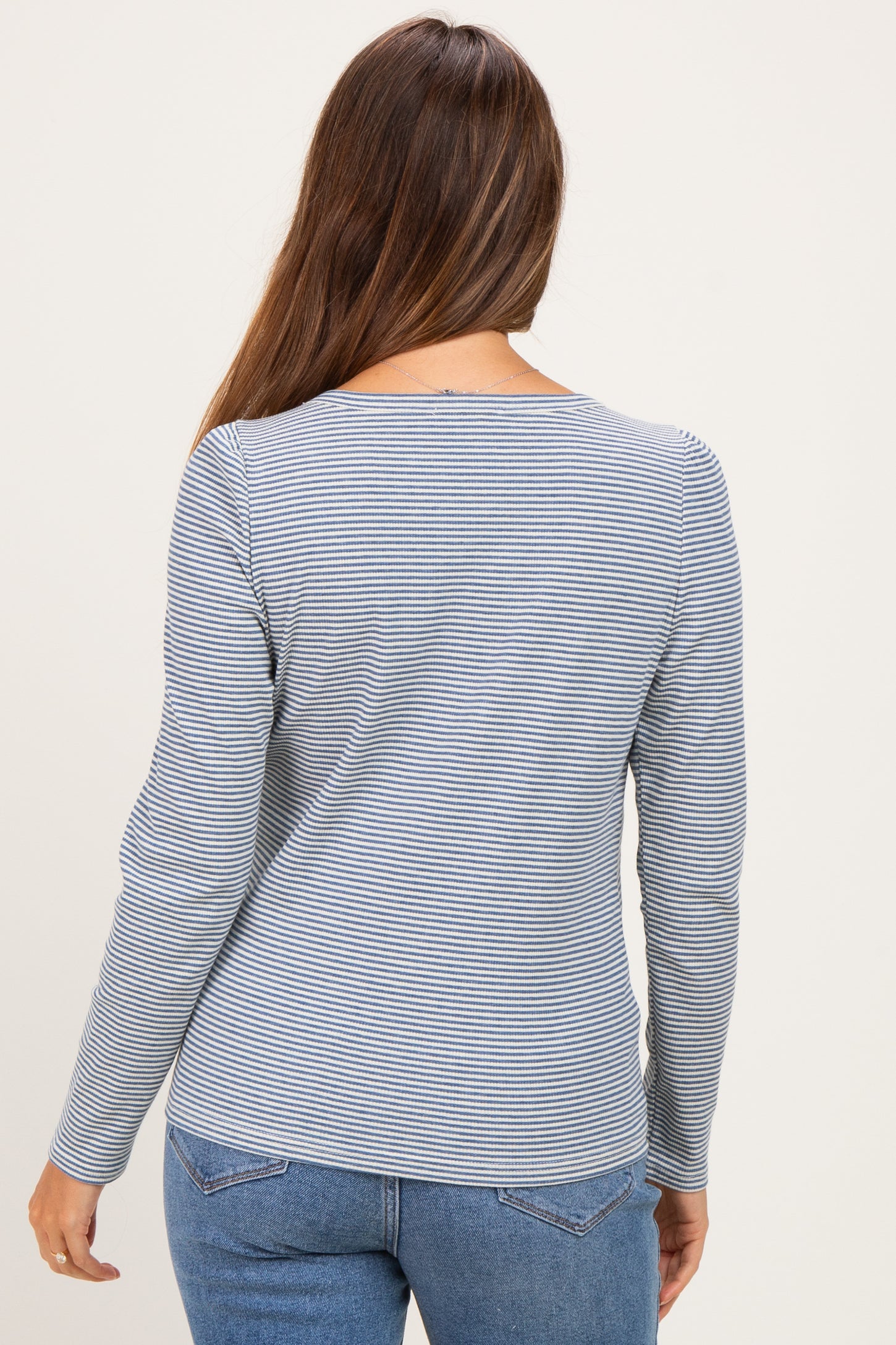 woman wearing a navy and white striped long sleeve maternity top, showing the back view with a fitted silhouette