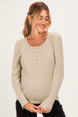 woman wearing a beige and cream striped maternity top with button details and a visible baby bump