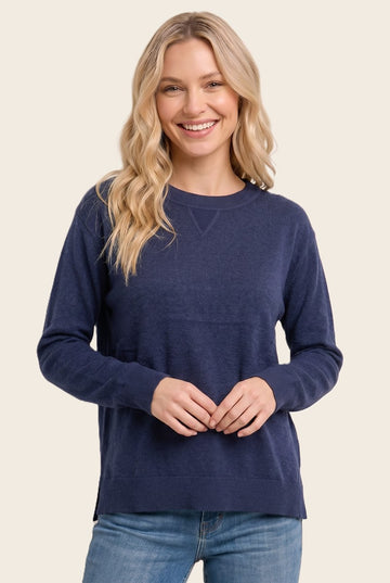 woman wearing a navy blue long sleeve sweater with a relaxed fit and side slits, smiling at the camera
