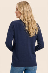 woman wearing a navy blue long sleeve cardigan with a relaxed fit and side slits, styled with light blue jeans