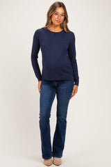 woman wearing a navy blue maternity sweater and dark blue flared jeans with a visible baby bump