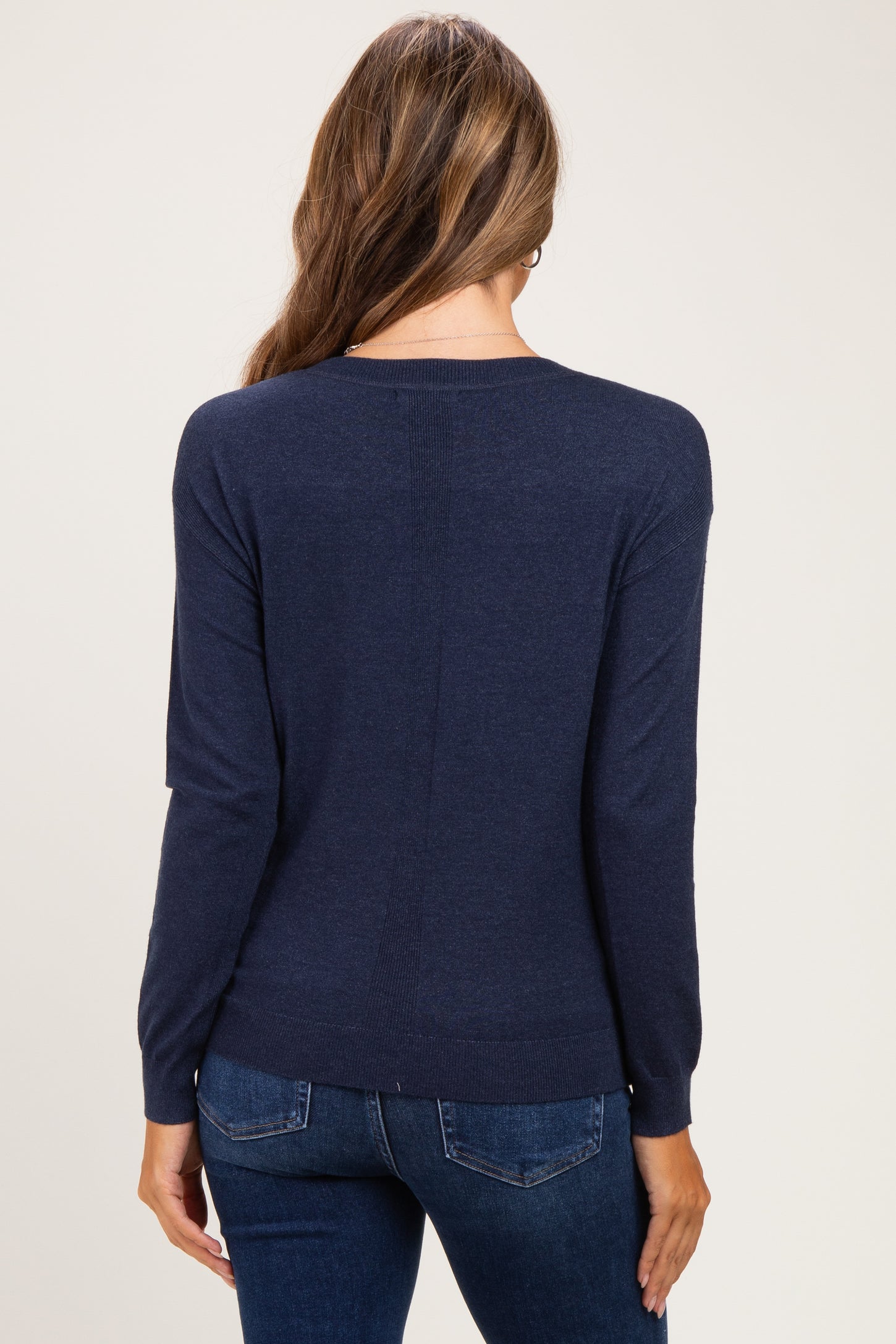 woman wearing a navy blue maternity sweater with long sleeves and a relaxed fit, seen from the back