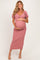 woman wearing a pink maternity dress with puff sleeves and a ruched side, holding her baby bump