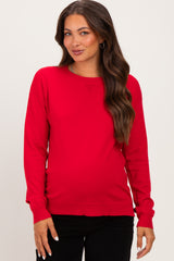 woman wearing a red maternity sweater with long sleeves and a fitted silhouette, showing her baby bump