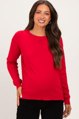 woman wearing a bright red long sleeve maternity sweater with a relaxed fit and smiling at the camera