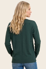 woman wearing a dark green sweater with a relaxed fit and ribbed details, shown from the back