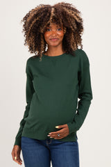 woman wearing a dark green maternity sweater and holding her baby bump
