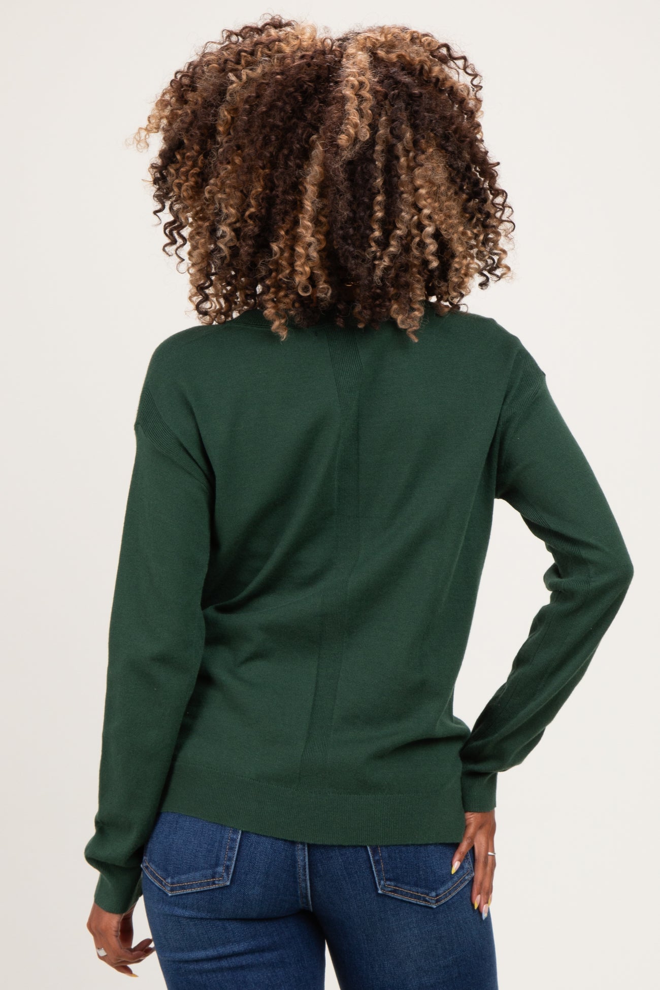 woman wearing a dark green maternity sweater with a fitted design and long sleeves, viewed from the back