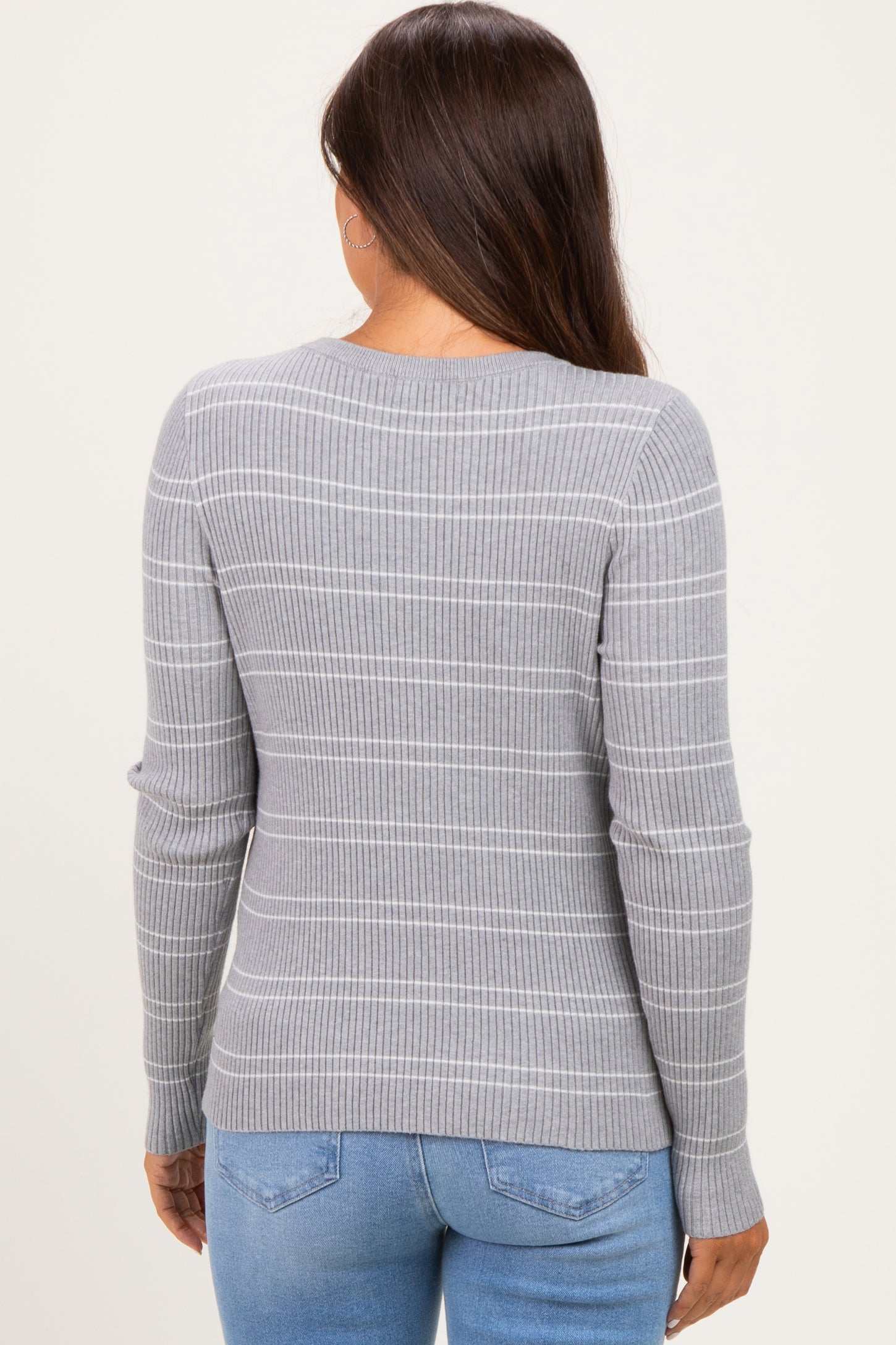 woman wearing a gray striped maternity sweater, viewing from the back, paired with blue jeans