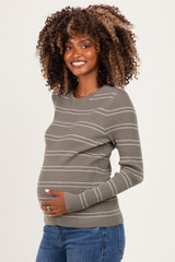 woman wearing a green and white striped maternity long sleeve top and holding her baby bump